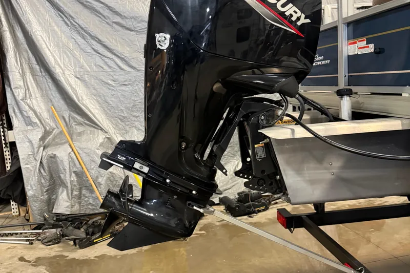 Slide: The Image of 2023 Sun Tracker Bass Buggy 18 DLX with Mercury outboard motor in a garage setting. - 5