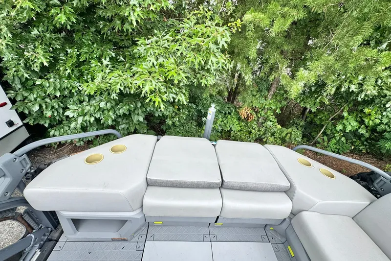 Slide: The Image of 2023 Sea-Doo Switch Cruise 21 seating area with cup holders, surrounded by lush greenery. - 16