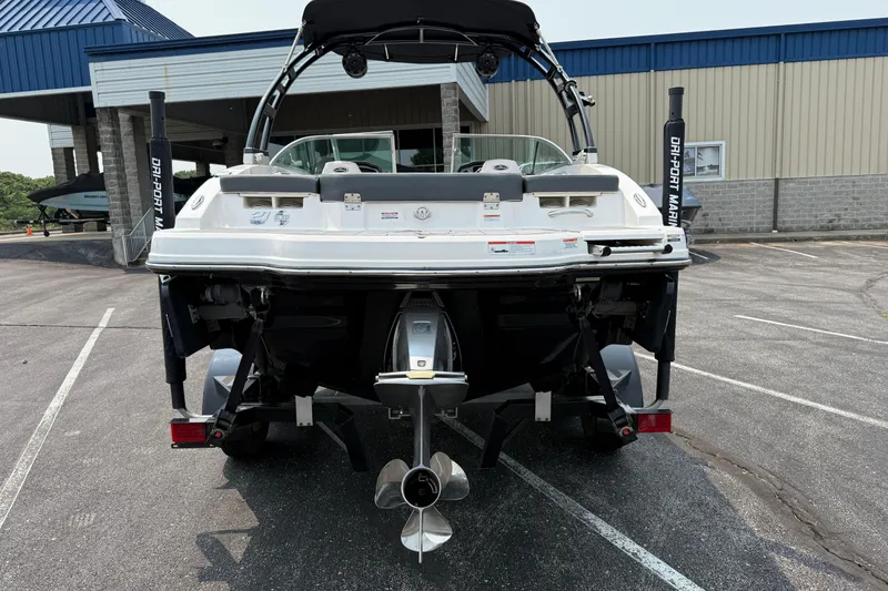 Slide: The Image of 2020 Chaparral 21 Surf boat rear view in parking lot, showcasing propeller and swim platform. - 7