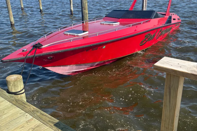 The Image of Red 1988 Fountain 38 speedboat docked on water, featuring sleek design and vibrant color. - 1