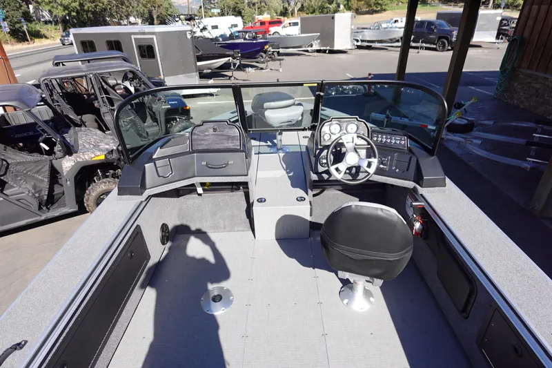 Slide: The Image of 2025 G3 Angler V1750SF boat interior with steering wheel and seating, parked outdoors. - 8