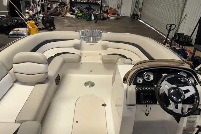 Slide: The Image of 2022 Starcraft Starstep 221 boat interior with spacious seating and modern dashboard in a garage setting. - 17