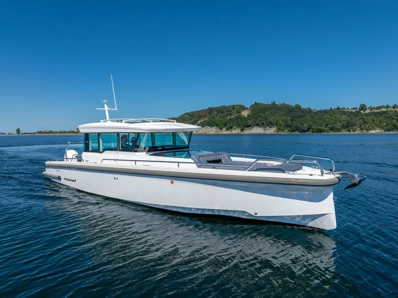 Slide: The Image of 2021 Axopar Cross Cabin boat cruising on a serene lake with lush green hills. - 1