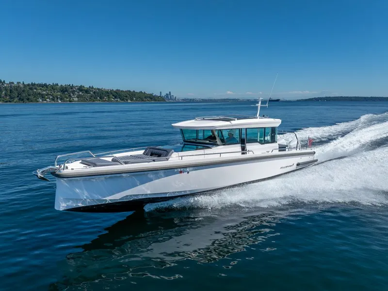 Slide: The Image of 2021 Axopar Cross Cabin boat cruising on a sunny day, with city skyline in background. - 10