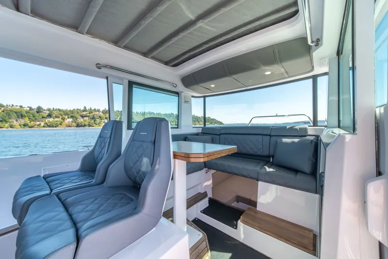 Slide: The Image of 2021 Axopar Cross Cabin interior with modern seating and scenic water view. - 12