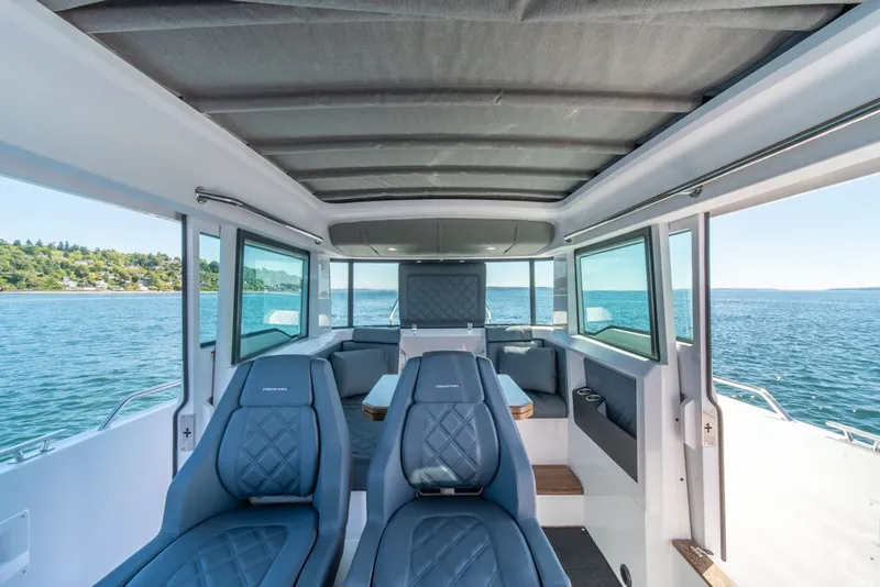 Slide: The Image of Interior of 2021 Axopar Cross Cabin boat with blue seating and panoramic windows. - 16