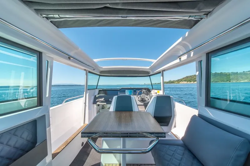 Slide: The Image of 2021 Axopar Cross Cabin interior with panoramic windows and seating, overlooking the ocean. - 17