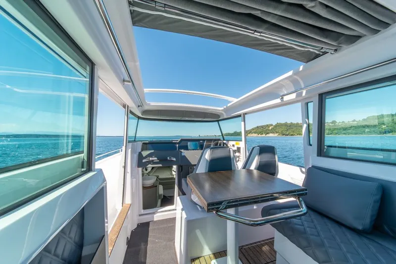 Slide: The Image of 2021 Axopar Cross Cabin interior with seating, table, and ocean view. - 18