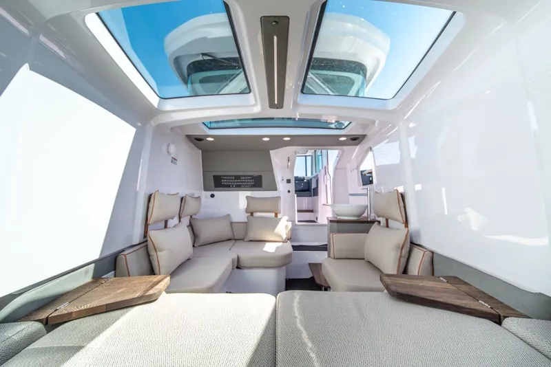 Slide: The Image of 2021 Axopar Cross Cabin interior with skylights, modern seating, and wooden accents. - 22