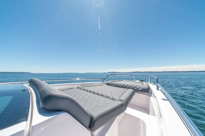 Slide: The Image of 2021 Axopar Cross Cabin boat with sun loungers on open water under clear blue sky. - 31