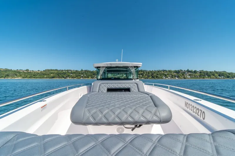 Slide: The Image of 2021 Axopar Cross Cabin boat with quilted seating, cruising on a clear blue lake. - 32