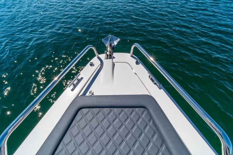 Slide: The Image of Bow of 2021 Axopar Cross Cabin boat with quilted seating, on sparkling blue water. - 33