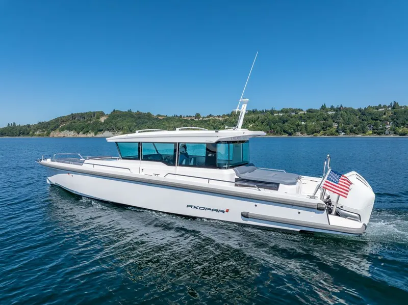 Slide: The Image of 2021 Axopar Cross Cabin boat cruising on a clear blue lake with scenic shoreline. - 38