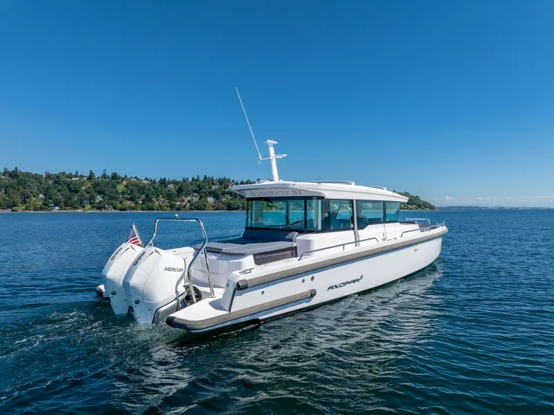Slide: The Image of 2021 Axopar Cross Cabin boat cruising on a clear blue lake with scenic shoreline. - 44
