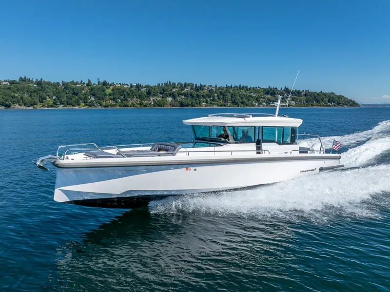 Slide: The Image of 2021 Axopar Cross Cabin boat cruising on a sunny day, with scenic shoreline in background. - 47