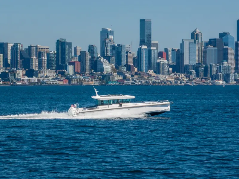Slide: The Image of 2021 Axopar Cross Cabin boat cruising with city skyline in the background. - 9