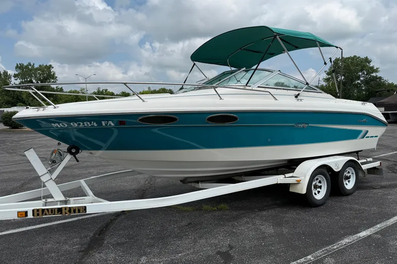 Slide: The Image of 1995 Sea Ray 220 Cuddy Cabin boat on trailer, teal and white design, parked outdoors. - 1