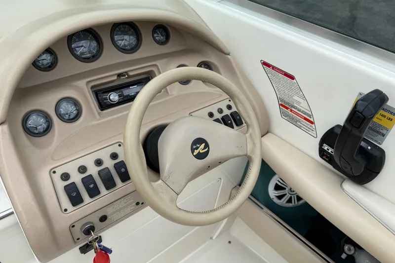Slide: The Image of 1995 Sea Ray 220 Cuddy Cabin dashboard with steering wheel and control panel. - 11