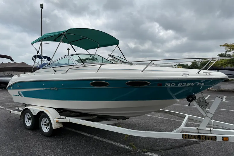 Slide: The Image of 1995 Sea Ray 220 Cuddy Cabin boat on trailer, teal and white, parked outdoors. - 2