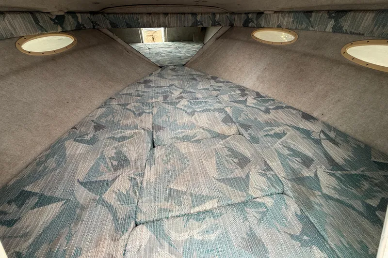 Slide: The Image of 1995 Sea Ray 220 Cuddy Cabin interior with patterned upholstery and round windows. - 22