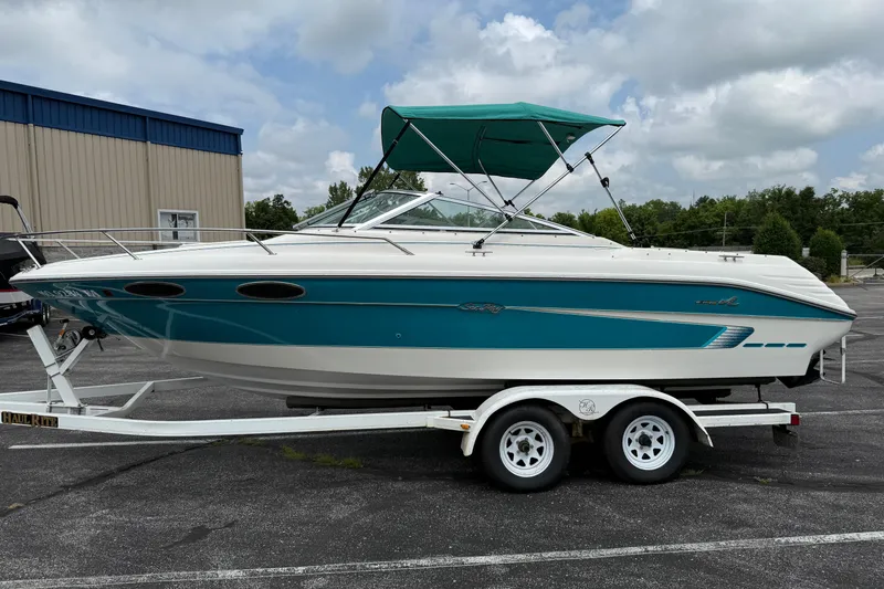 Slide: The Image of 1995 Sea Ray 220 Cuddy Cabin boat on trailer, teal and white design, parked outdoors. - 4