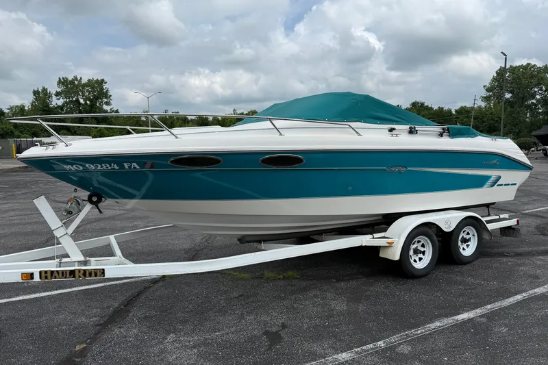 Slide: The Image of 1995 Sea Ray 220 Cuddy Cabin boat on trailer, parked in a lot under cloudy skies. - 5
