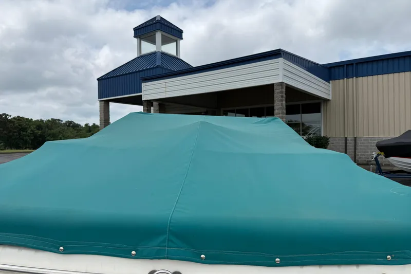 Slide: The Image of 1995 Sea Ray 220 Cuddy Cabin boat with teal cover, parked near a building. - 7