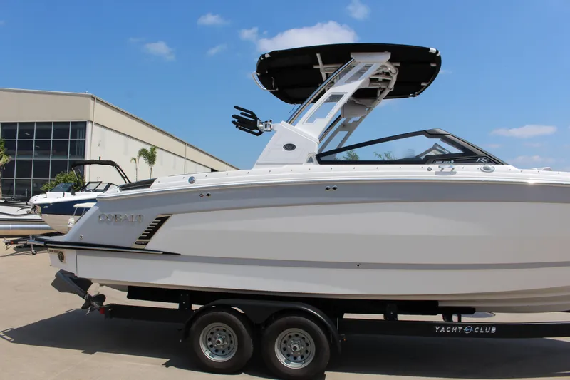 Slide: The Image of 2025 Cobalt R8 Surf boat on trailer, displayed outdoors under clear blue sky. - 12