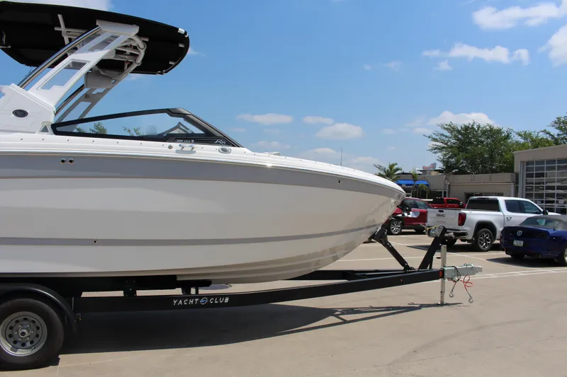 Slide: The Image of 2025 Cobalt R8 Surf boat on trailer in parking lot under clear blue sky. - 13