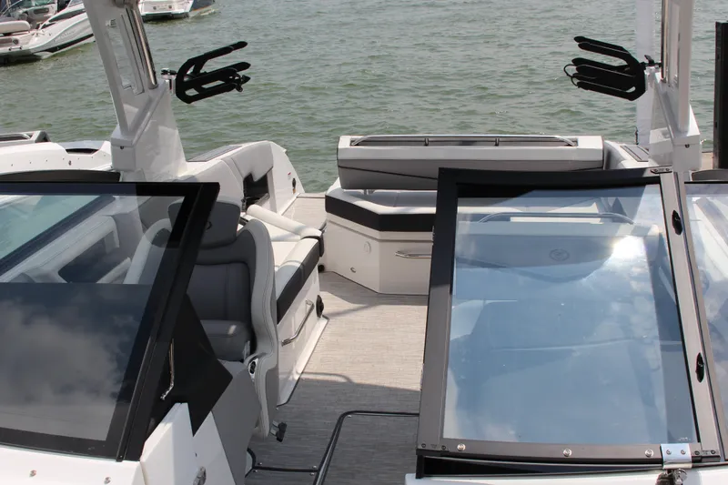 Slide: The Image of 2025 Cobalt R8 Surf boat interior with seating and glass windshields on a sunny day. - 32