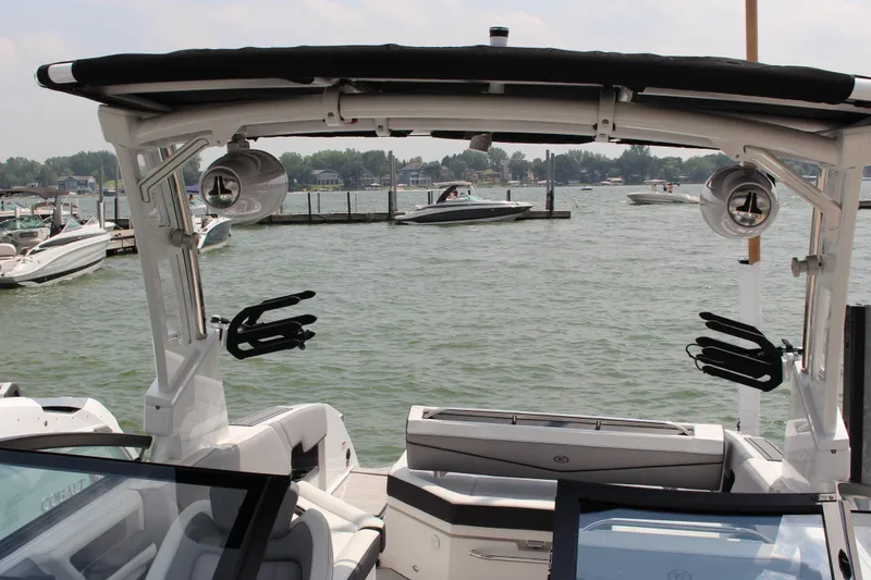 Slide: The Image of 2025 Cobalt R8 Surf boat on a lake, surrounded by other boats and docks. - 33