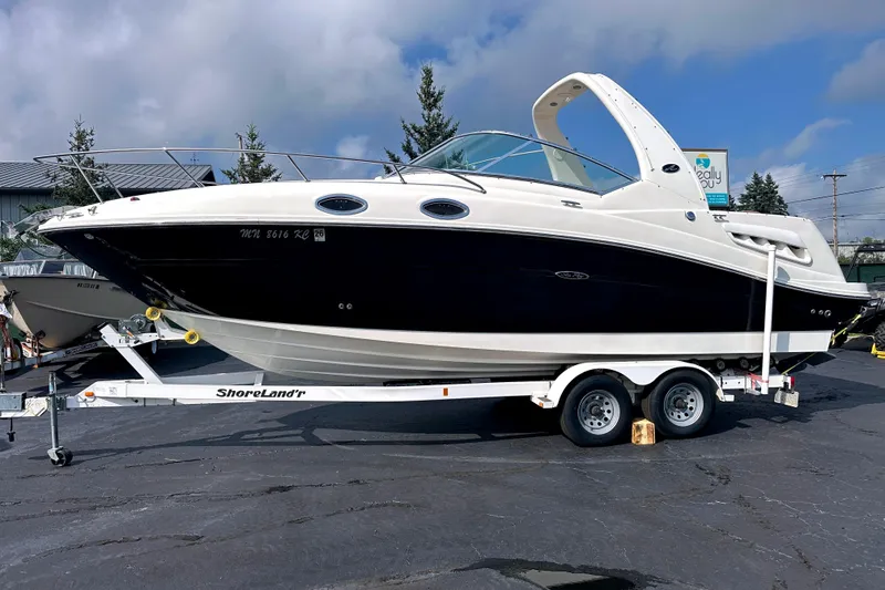 The Image of 2006 Sea Ray 260 Sundancer boat on trailer, parked outdoors under cloudy sky. - 0