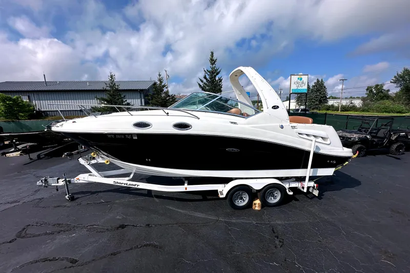 Slide: The Image of 2006 Sea Ray 260 Sundancer boat on trailer, parked outdoors under cloudy sky. - 2