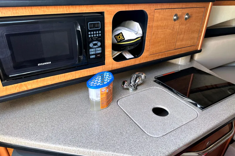 Slide: The Image of 2006 Sea Ray 260 Sundancer interior with microwave, sink, and storage cabinets. - 23