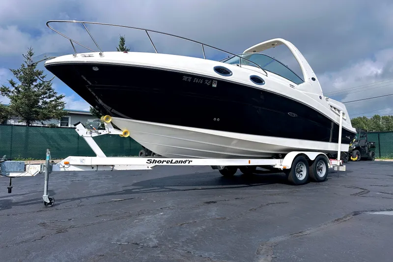 Slide: The Image of 2006 Sea Ray 260 Sundancer boat on trailer, parked outdoors under cloudy sky. - 3