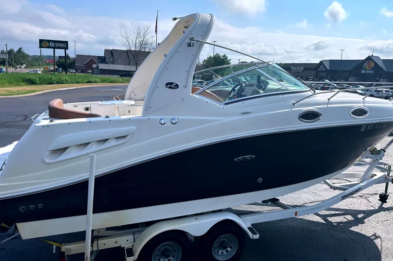 Slide: The Image of 2006 Sea Ray 260 Sundancer boat on trailer, parked outdoors near shops. - 8