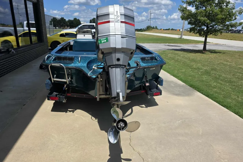 Slide: The Image of 1994 Ranger 482 V boat with outboard motor, parked on concrete near grassy area. - 9