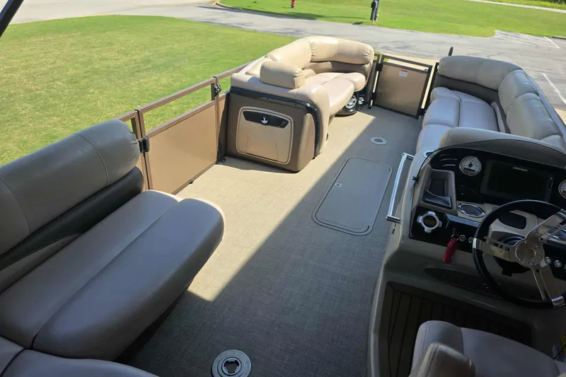 Slide: The Image of 2015 Regency 254 LE3 pontoon boat interior with plush seating and steering console. - 6