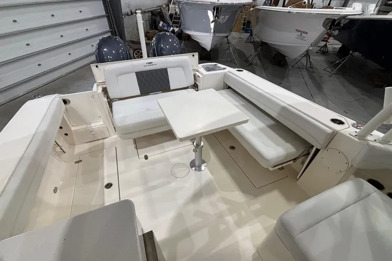 Slide: The Image of 2020 Cobia 280 Dual Console boat interior with seating and table in a showroom. - 12