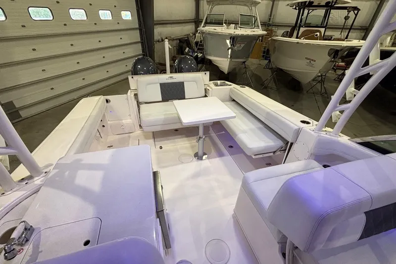 Slide: The Image of 2020 Cobia 280 Dual Console boat interior with seating and table in a garage setting. - 13