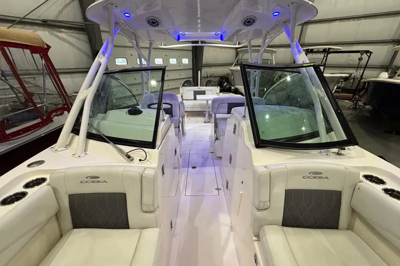Slide: The Image of 2020 Cobia 280 Dual Console boat interior with seating and windshield in a storage facility. - 18