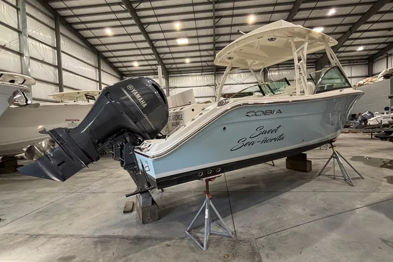 Slide: The Image of 2020 Cobia 280 Dual Console boat in storage, featuring Yamaha outboard motor. - 6