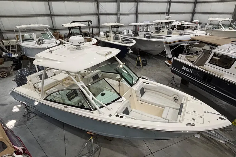 Slide: The Image of 2020 Cobia 280 Dual Console boat in indoor showroom with other vessels. - 8