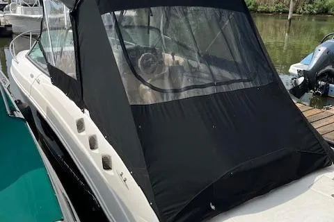 The Image of 2012 Chaparral 225 SSi boat with black canopy docked on calm water. - 1