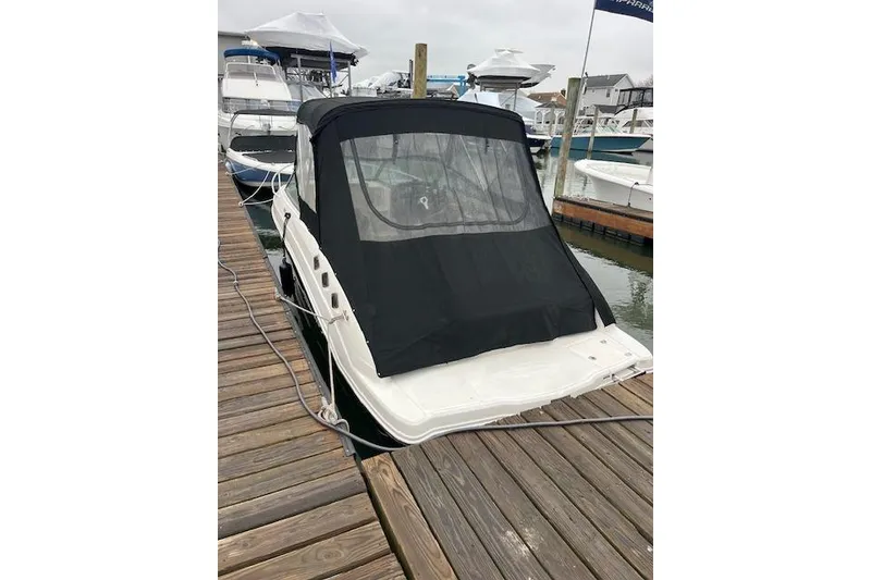 Slide: The Image of 2012 Chaparral 225 SSi boat docked with black cover, marina background. - 18