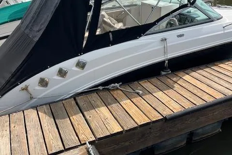 Slide: The Image of 2012 Chaparral 225 SSi boat docked, featuring sleek white design and black canopy. - 2