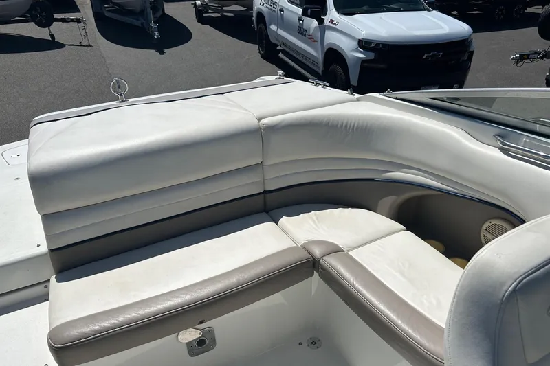 Slide: The Image of 2001 Cobalt 227 boat interior with white and gray seating, parked near vehicles. - 12