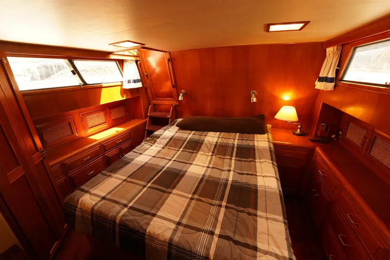 Slide: The Image of 1986 Ocean Alexander 40 Double Cabin bedroom with wood paneling and plaid bedding. - 22