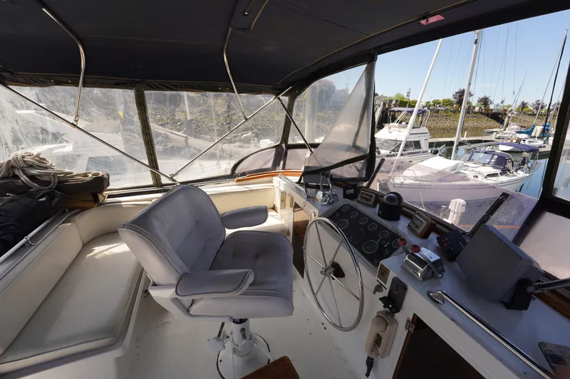 Slide: The Image of 1986 Ocean Alexander 40 Double Cabin helm with steering wheel, controls, and marina view. - 8