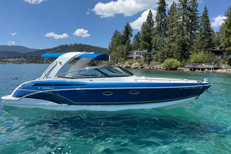 Slide: The Image of 2018 Formula 330 Crossover Bowrider on a scenic lake with forested shoreline. - 0